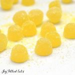 Sour Lemon Gumdrops on a white surface sprinkled with sugar coating close up