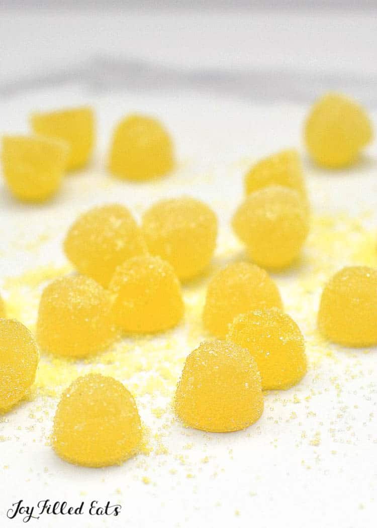 Sour Lemon Gumdrops on a white surface sprinkled with sugar coating close up