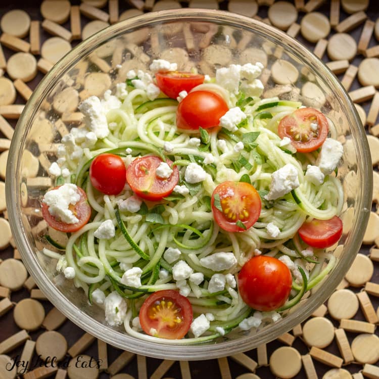 Zucchini salad with feta and tomatoes in a glass bowl