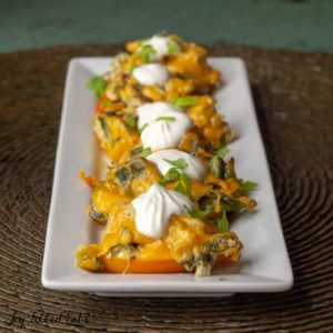 Chicken stuffed peppers topped with dollops of sour cream arranged on a platter