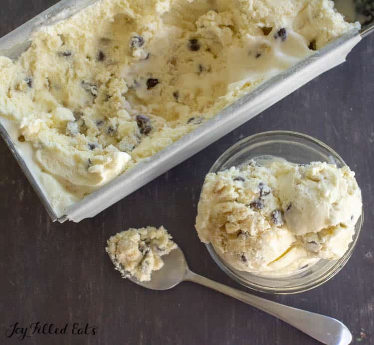cookie dough ice cream container next to a bowl with two scoops of ice cream and a spoonful of ice cream
