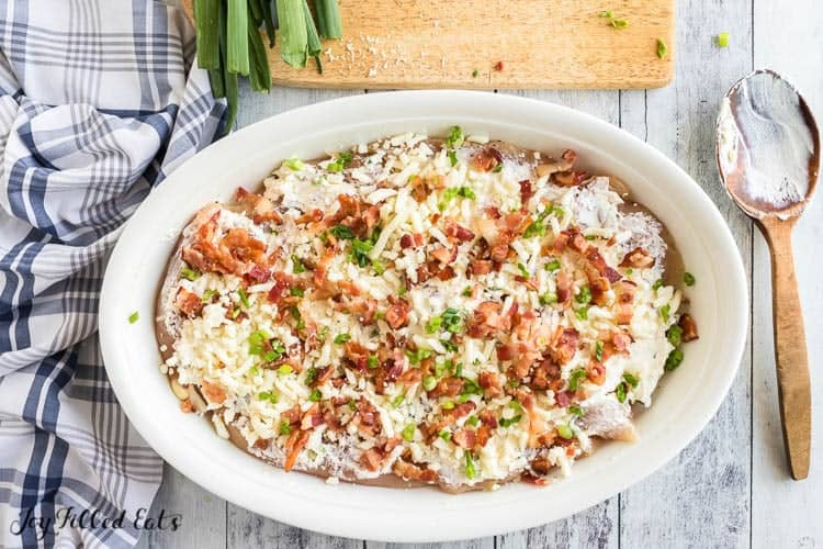 casserole topped with cheese bacon and scallions before baking