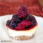 healthy cheesecake topped with a pyramid of mixed berries on a white plate close up