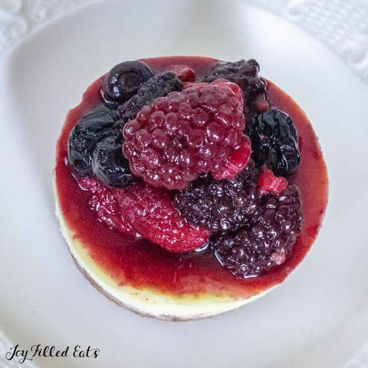 cheesecake topped with mixed berries on a white plate from above