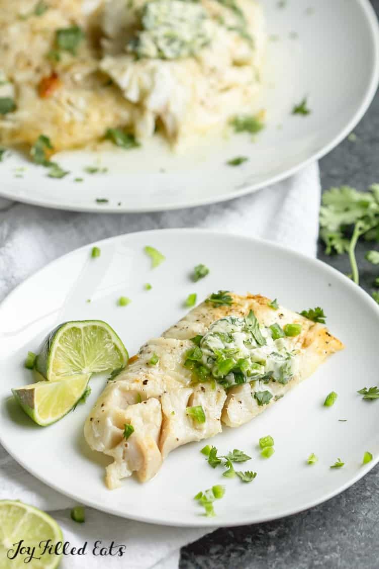plate of pan-seared cod topped with cilantro-lime butter served with lime wedges