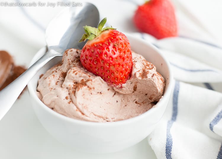 bowl of chocolate whipped cream with a spoon topped with a whole strawberry
