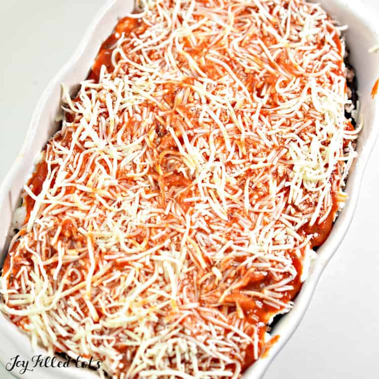 eggplant lasagna in a casserole dish topped with shredded cheese before baking