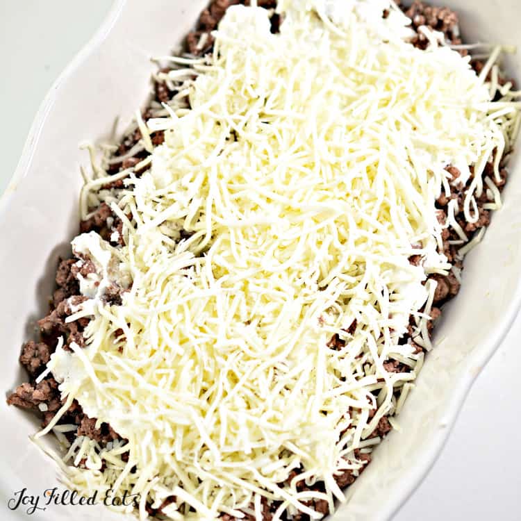 casserole dish of eggplant lasagna layers with shredded cheese layered onto ground meat