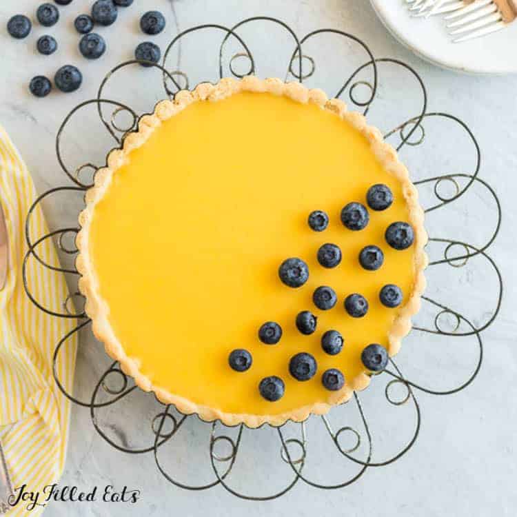 Lemon Curd Tart decorated with blueberries on a wire cake stand from above