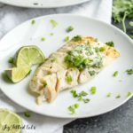 plate of pan-seared cod topped with cilantro-lime butter served with lime wedges