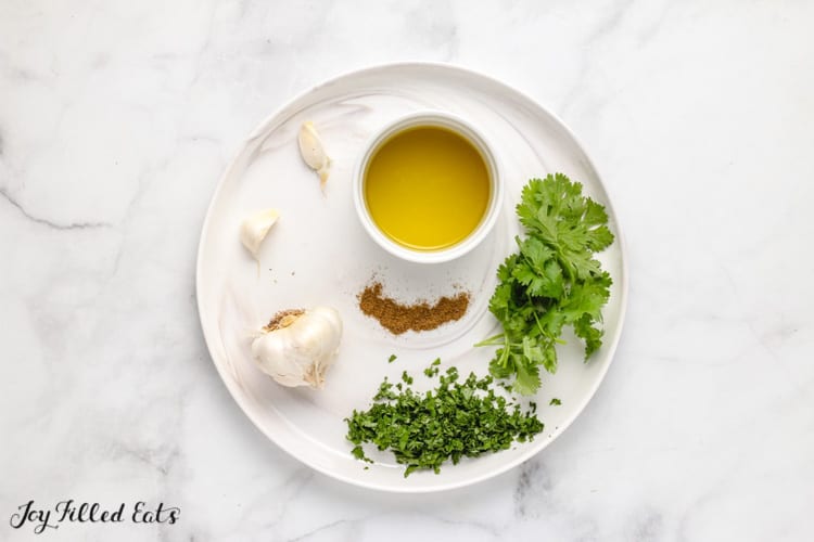 chimichurri sauce ingredients arranged individually on a white plate