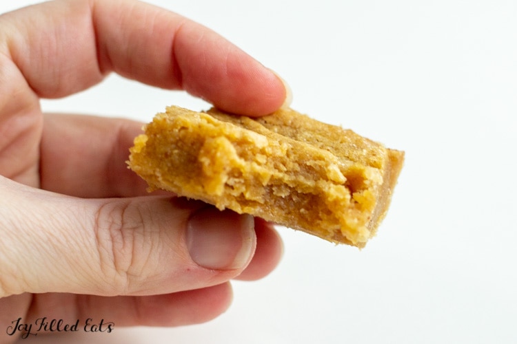 hand holding white chocolate peanut butter blondie with bite missing