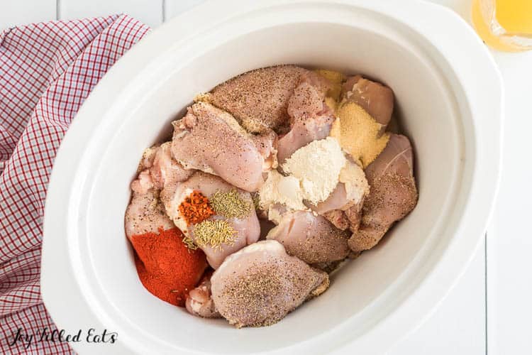 overhead view of crockpot filled with chicken pieces and seasoning