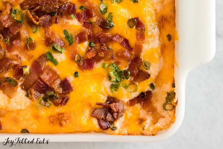 casserole dish of loaded cauliflower casserole topped with bacon pieces close up