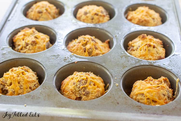 a muffin tin with sausage muffins cooked inside the muffin molds