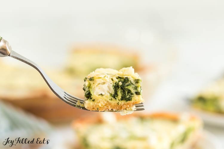 fork holding up a bite of spinach and feta quiche