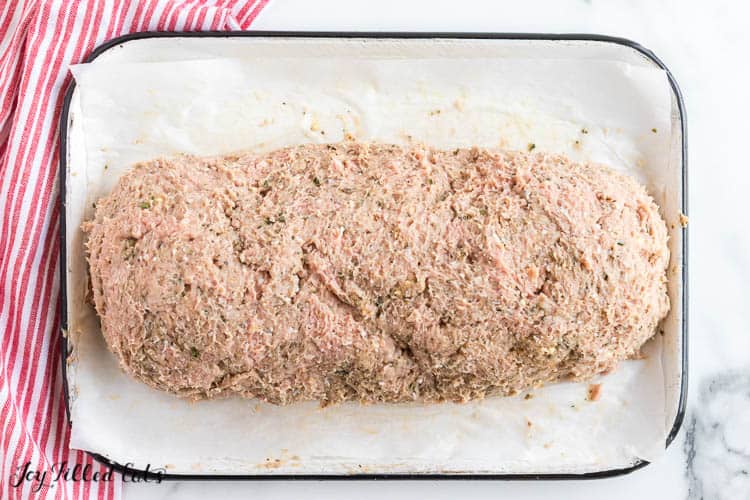 stuffed meatloaf ingredients shaped into loaf form in a shallow baking dish before cooking