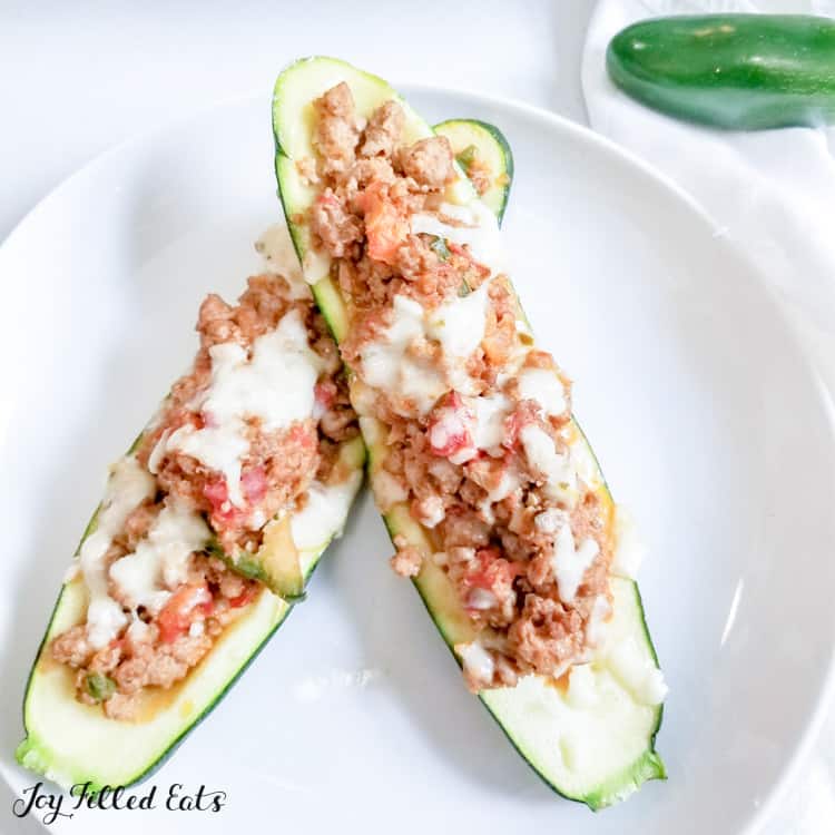 Two Taco Zucchini Boats resting on top of each other on a shallow white dish