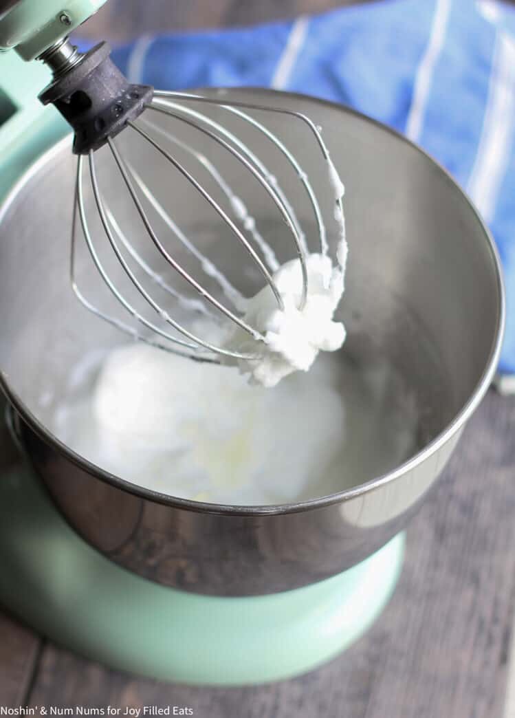 stand mixer and whisk with ricotta cheese mixture in bowl and on tip of whisk