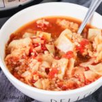 close up of cabbage roll soup in white soup bowl with spoon