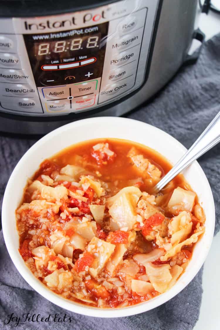 cabbage roll soup in white bowl with spoon in front of instant pot