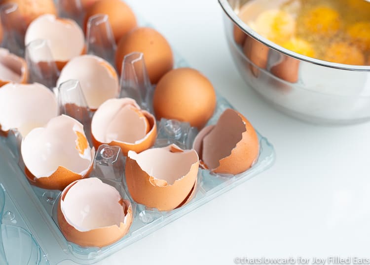 Carton of egg shells next to mixing bowl of cracked raw eggs