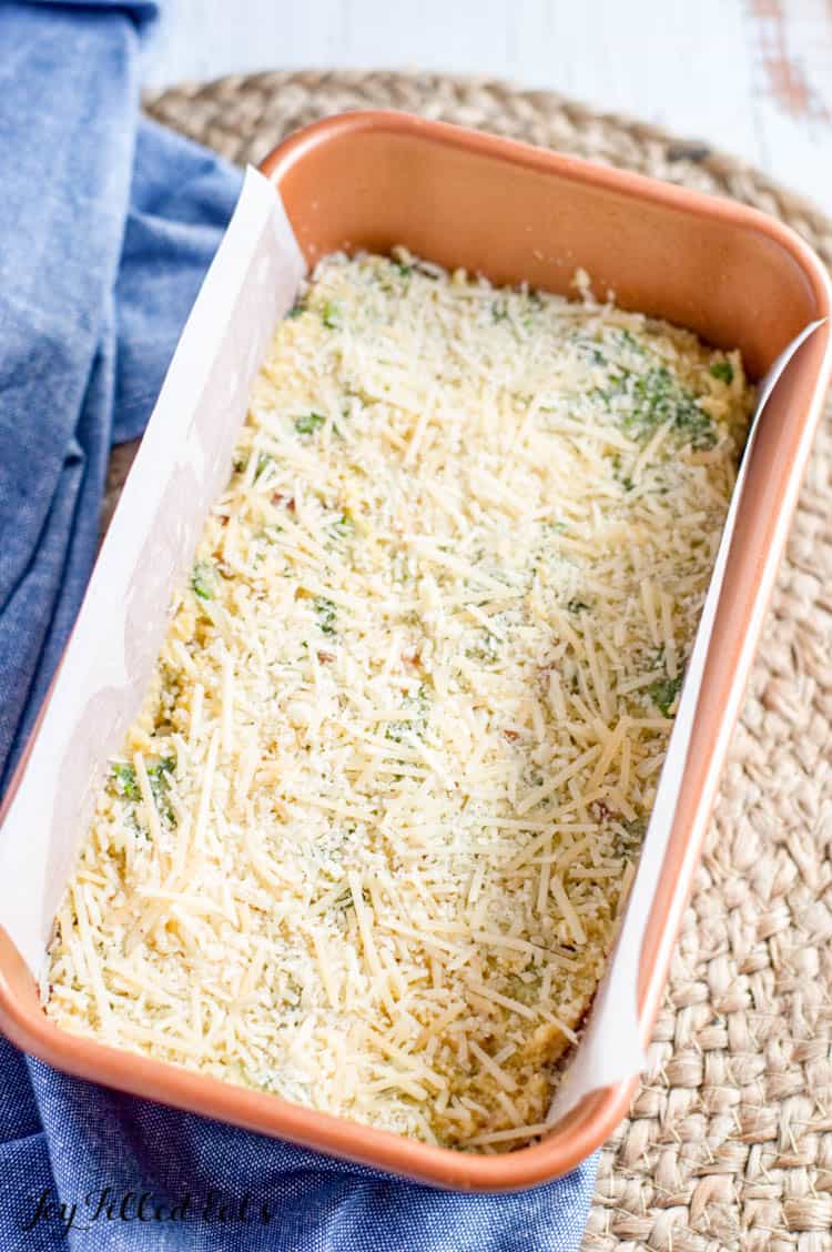Breakfast Bread dough in parchment lined bread pan, topped with shredded cheese
