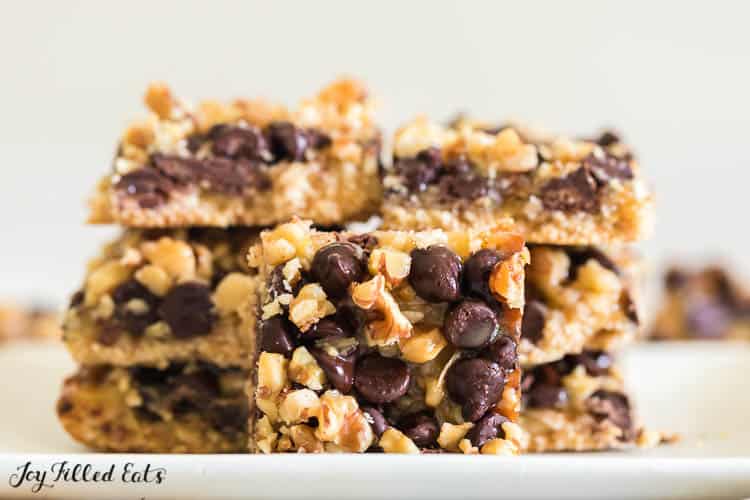 magic cookie bar square in front of two stacks of magic cookie bars on a white plate
