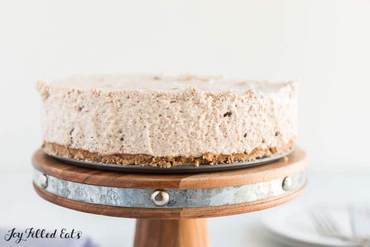 No Bake Cannoli Cheesecake sitting atop a wooden cake platter