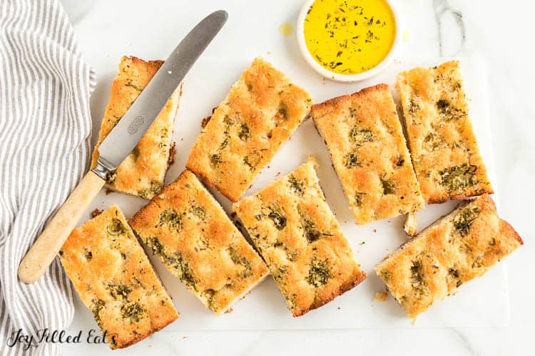 keto garlic bread bars on table surrounded by striped napkin, butter knife and herb butter