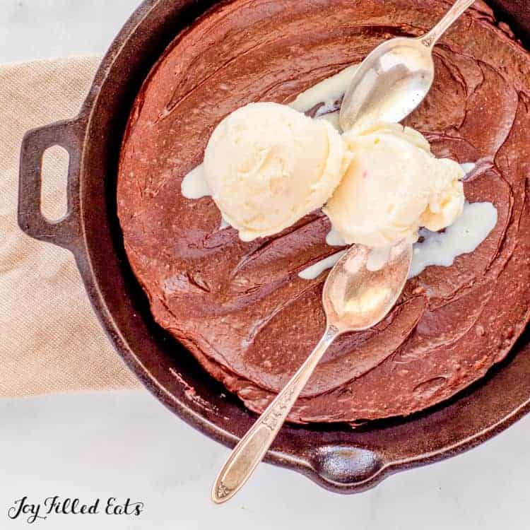 close up of skillet brownie with two scoops of ice cream and two spoons