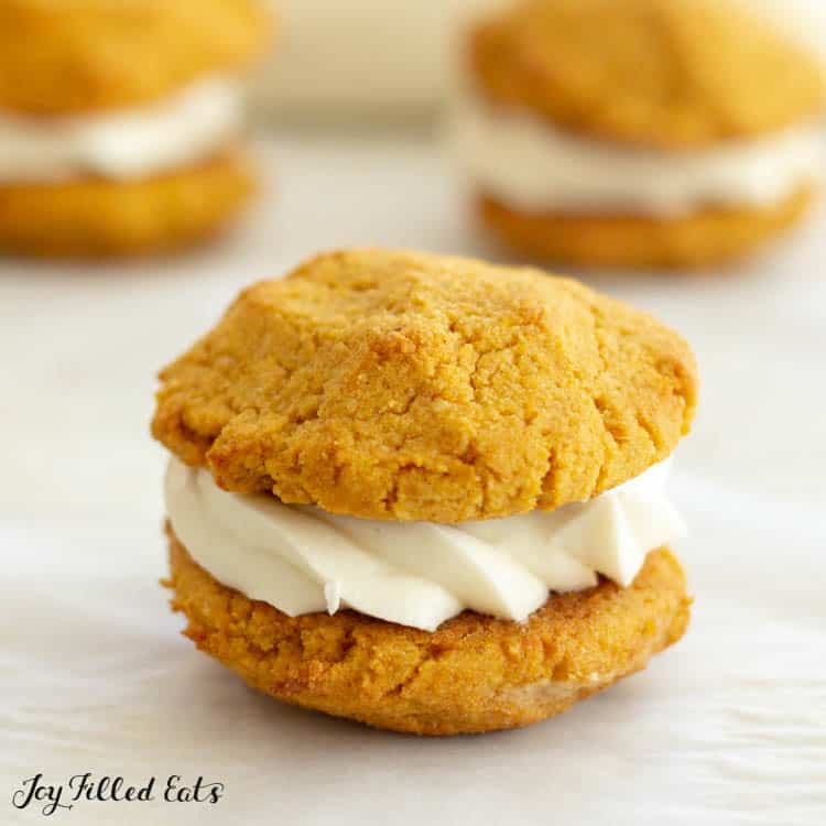 close up of pumpkin cookies sandwiching cream cheese frosting filling