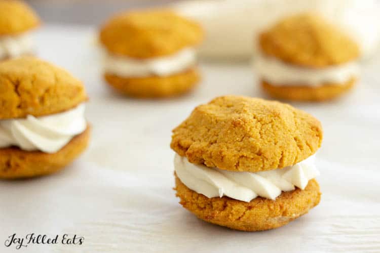 keto pumpkin cookies with filled cream cheese frosting scattered on table