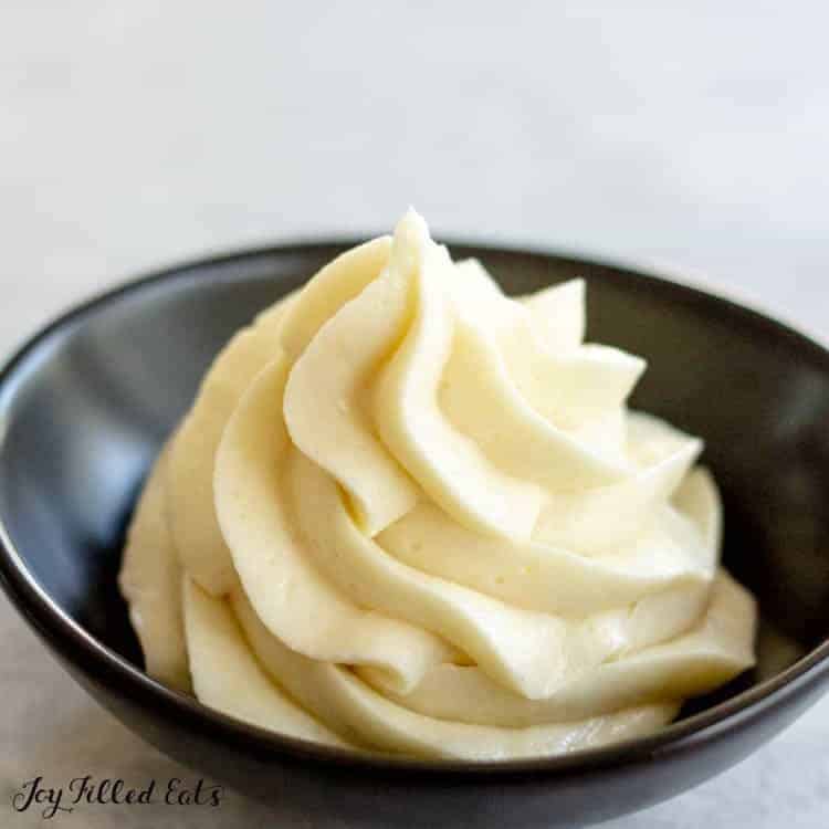 piped cream cheese frosting in small black bowl