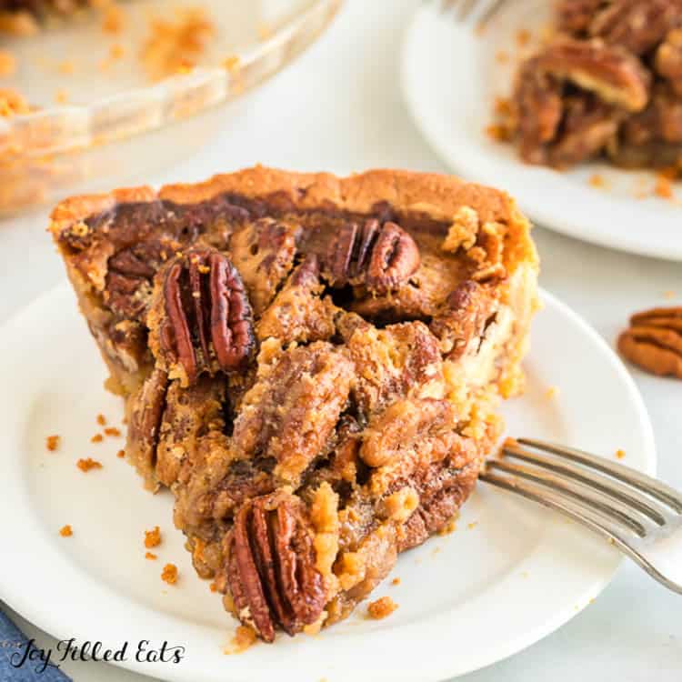 Close up on keto pecan pie slice on white plate with fork