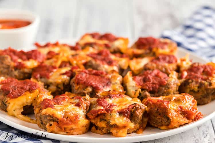 close up of platter serving mini meatloaves covered in a red sauce and melted cheese