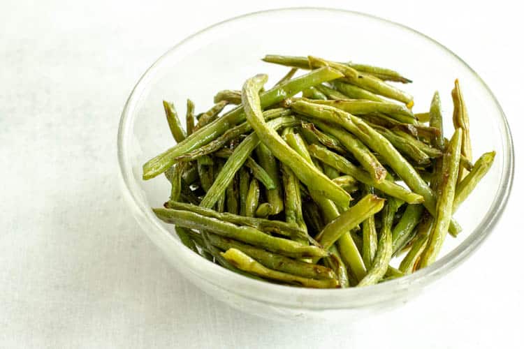 over roasted green beans in a glass bowl