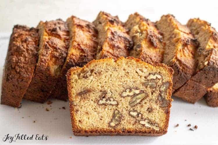 slices of low carb keto banana bread standing upright with one slice leaning on pile exposing nuts within bread