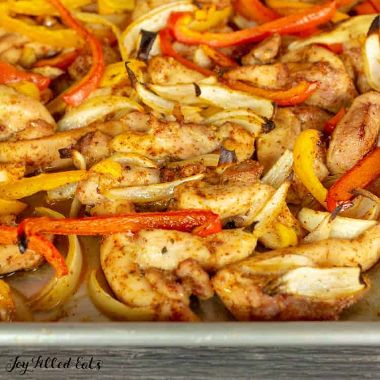 Sheet pan of seasoned chicken, peppers and onions