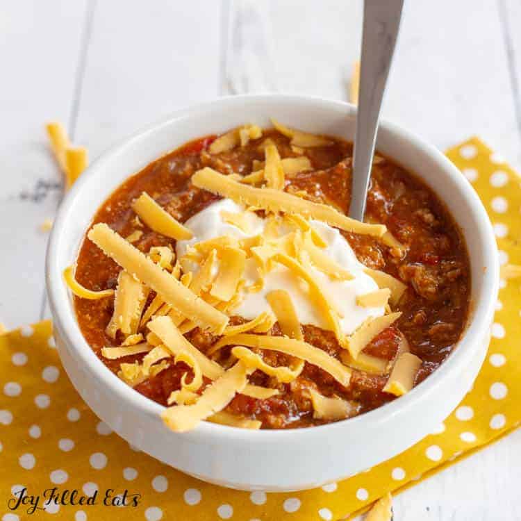 bowl and spoon of instant pot turkey chili topped with sour cream and shredded cheese