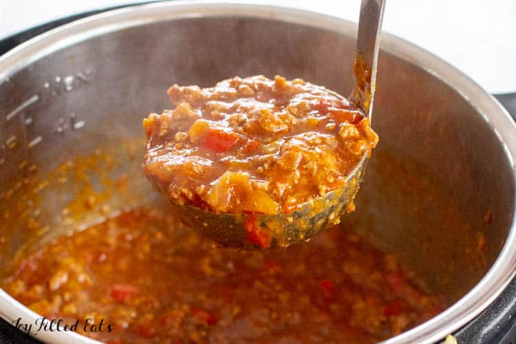 Ladle full of instant pot turkey chili scooping out of instant pot of chili