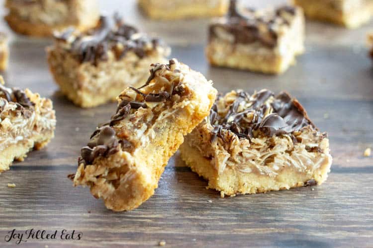 Scattered Homemade Samoa Bars with one propped on its side with a bite missing