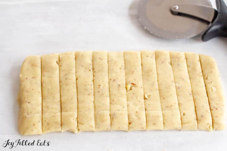 Keto Almond Shortbread cookie batter rolled and cut into stripes with pizza cutter