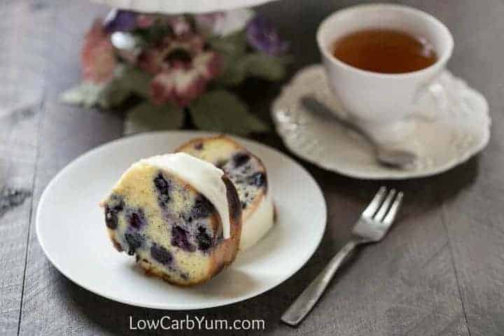 Lemon blueberry pound cake on small white plate next to cup of tea
