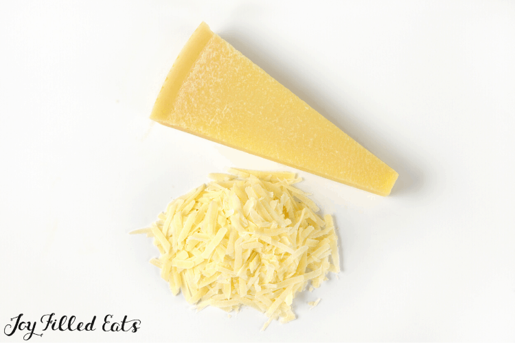 Parmesan wedge with pile of shredded Parmesan next to wedge