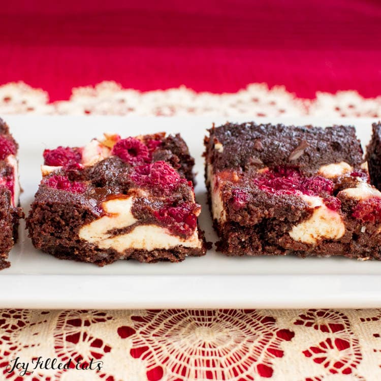 dark chocolate raspberry cheesecake brownies lined on a platter close up