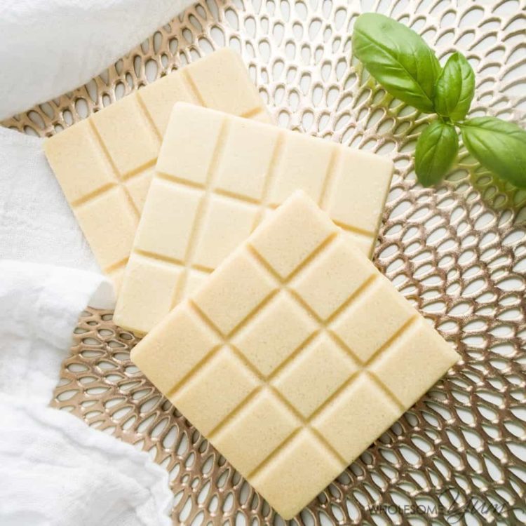 Close up of homemade sugar free white chocolate bars next to a piece of mint on a decorative place mat