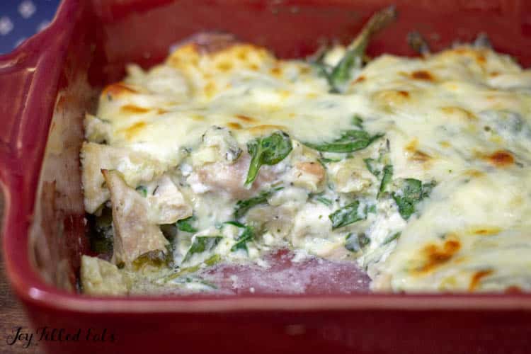 Inside look of spinach and artichoke chicken casserole within a red casserole dish