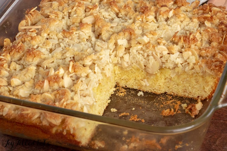 Almond Crumb Cake baked in a glass dish with a piece missing