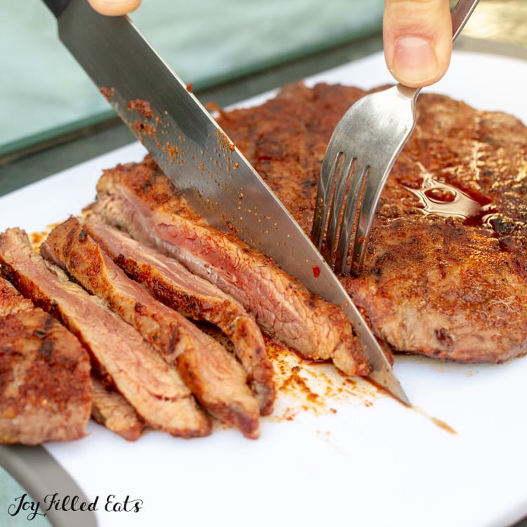 steak with fajita seasoning being sliced on a cutting board